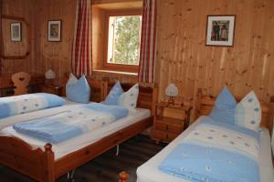 twee bedden in een kamer met houten wanden en een raam bij Pederü in San Vigilio Di Marebbe