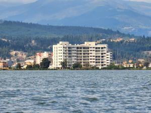 a large white building on the shore of a body of water at Apartamento de lujo frente al Lago Sochagota in Paipa