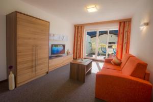 ein Wohnzimmer mit einem orangenen Sofa und einem TV in der Unterkunft Apart Mado in Längenfeld