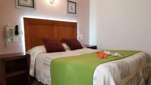 a bedroom with a bed with a green blanket and flowers on it at Hostal Greco Gran Vía Madrid in Madrid