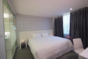 a bedroom with a white bed and a window at Hotel Purity in Xinzhuang