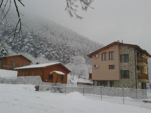 a building in the snow next to a mountain at Mini Complex Rilski Terasi in Sapareva Banya