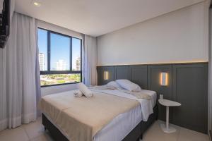 a bedroom with two beds and a large window at Milos Comfort Club in Piçarras