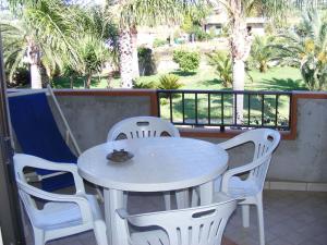 a white table and chairs on a balcony with palm trees at Appartamenti Garden in Capo Vaticano