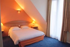 ein Hotelzimmer mit einem Bett und einem Fenster in der Unterkunft Hotel Restaurant l'Amandois in Saint-Amand-Montrond + 10 Fotos