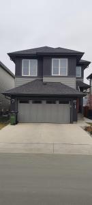 a large house with two garage doors in a driveway at Contemporary Two Bedroom Basement Suite in Edmonton