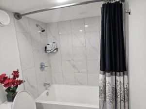 a bathroom with a tub and a shower with a shower curtain at Contemporary Two Bedroom Basement Suite in Edmonton +44 photos