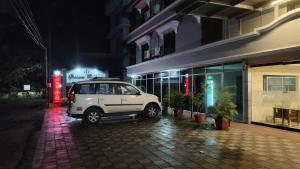 a white car parked outside of a building at night at Shalimar Residency in Cochin