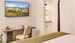 a bedroom with a bed and a desk with a television on the wall at Canoe Place Inn & Cottages in Hampton Bays