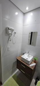 a white bathroom with a sink and a mirror at Vila Caiçara Apê a 40m da Praia in Solemar