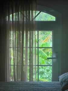 a bedroom window with a bed and a window with a tree at Village Guest House in Corfu