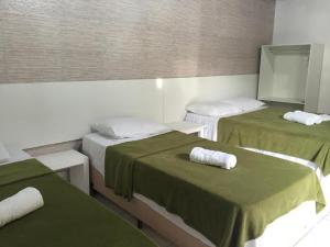 Habitación con 2 camas, sábanas verdes y toallas. en Pousada Villa Joia en Barra de São Miguel