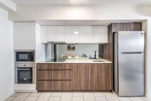 穆卢拉巴First Light Mooloolaba 9th floor apartment with ocean views的配有白色橱柜和不锈钢冰箱的厨房