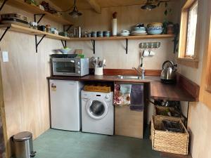 eine Küche mit Waschmaschine und Mikrowelle in der Unterkunft Rustic country Cottage in Haumoana