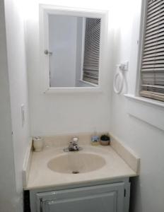 ルイスビルにあるPrivate Room Near to Downtown Churchill Downs UofL Airport &Kentucky Expo Centerの洗面台と鏡のある白いバスルーム