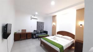 a bedroom with a bed and a chair and a television at Hotel Green Prundi in Labuan Bajo