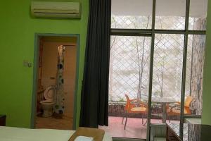Un dormitorio con paredes verdes y una ventana con vista a un patio. en Hotel O Saril Riverside HomestayNearLapangan Musara Alun, en Rawe