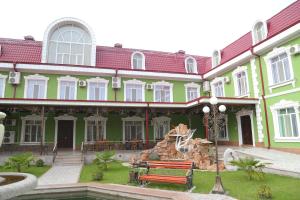 ein großes, grünes Gebäude mit einem Brunnen davor in der Unterkunft Sipehr Hotel in Chkalovsk