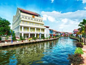 a building next to a river in a city at RC Hotel Melaka in Melaka