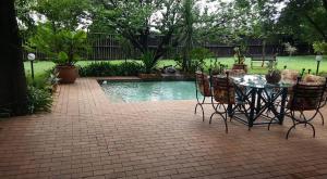 a patio with a table and chairs next to a pool at Midrand Wild Goose Guest House B&B in Midrand