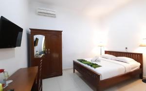 a bedroom with a bed and a desk and a television at Hotel Green Prundi in Labuan Bajo