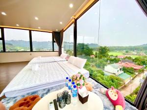 a bedroom with a bed and a large window at Amore Mio Mộc Châu Hotel in Làng Môn