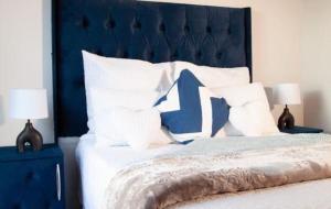a bed with a blue head board and white pillows at Comfortable lovely apartment in Johannesburg