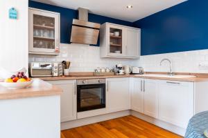 a kitchen with white cabinets and a blue wall at The Summerhouse in Milford on Sea