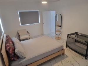 拉罗汤加Te Aro Villa in Muri 1 &2的卧室里有一张床、一面镜子和一把椅子
