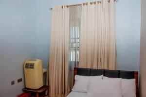 a bedroom with a bed and a window with curtains at Exclusive Villa 24Hr Solar Electricity in Umuahia