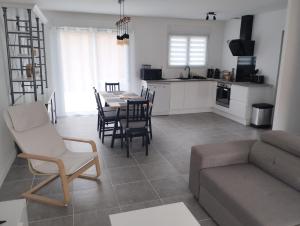 a living room with a table and chairs and a kitchen at Maison neuve proche BORDEAUX 3 étoiles in Macau