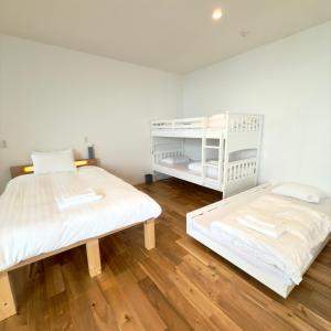 two beds in a room with wooden floors at Seaside Inn KOKOMO in Hakodate