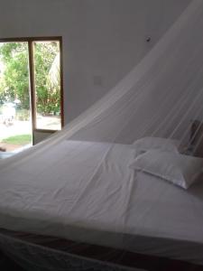 1 dormitorio con cama blanca y mosquitera en Green House Rooms, en Mirissa