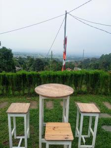 PalasariTenda Kebun Sukaharja Bogor的一张桌子和两张凳子摆放在田野上。