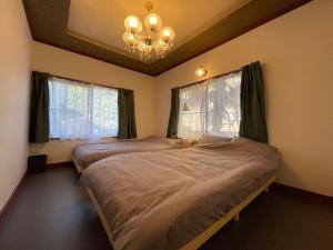 涩川市Private Lodge 春夏秋冬 -SHIKI-的一间有两张床和一盏枝形吊灯的卧室