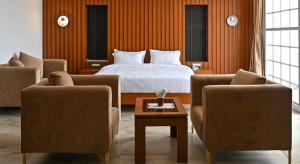 a bedroom with a bed and two chairs and a table at The Caligo resort coorg in Madikeri +43 photos