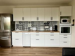 a kitchen with white cabinets and a stainless steel refrigerator at Hyper Centre - Draps Inclus - Fibré - Parking - Local Vélos - Jusqu'à 6 personnes in Saint-Brevin-les-Pins