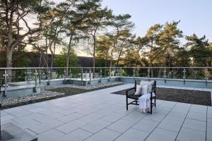 a chair on a patio with trees in the background at Maisonette-Apartment A11 - zwei Schlafzimmer, zwei Bäder, zwei Balkone & zwei Terrassen im "Pine Hill Resort" in Zirchow