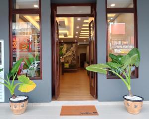 a hallway with two potted plants in a store at Sh Garden Hotel in Tanah Merah