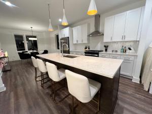 a kitchen with white cabinets and a large island with bar chairs at New Elevations Rooftop 5 Min to Downtown Nash in Nashville