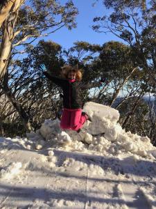 a little girl jumping on a pile of snow at Alpine Chalet 3BR with Heated Floors and Fast Wi-Fi in Mount Buller +40 photos