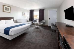 a hotel room with a bed and a television at Travelodge by Wyndham Cochrane Ontario in Cochrane