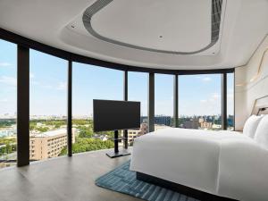 a bedroom with a white bed and a flat screen tv at Hilton Shanghai Hongqiao International Airport in Shanghai