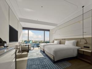 a hotel room with two beds and a flat screen tv at Hilton Shanghai Hongqiao International Airport in Shanghai