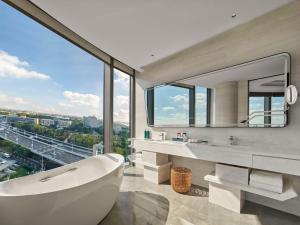 a white bathroom with a tub and a large window at Hilton Shanghai Hongqiao International Airport in Shanghai