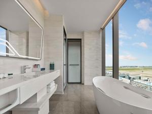 a white bathroom with a tub and a large window at Hilton Shanghai Hongqiao International Airport in Shanghai
