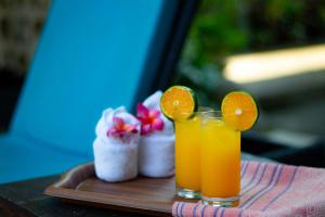 two glasses of orange juice on a wooden tray at Mina Pelasa Hotel in Legian