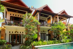 a house with a pool in front of it at Mina Pelasa Hotel in Legian