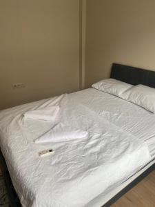 a bed with white sheets and a remote control on it at meva pansiyon in Küçük Çığlı