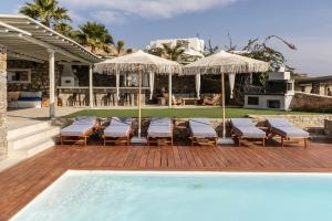 a pool with chairs and umbrellas next to a house at Villa Assa -Mykonos in Mýkonos City